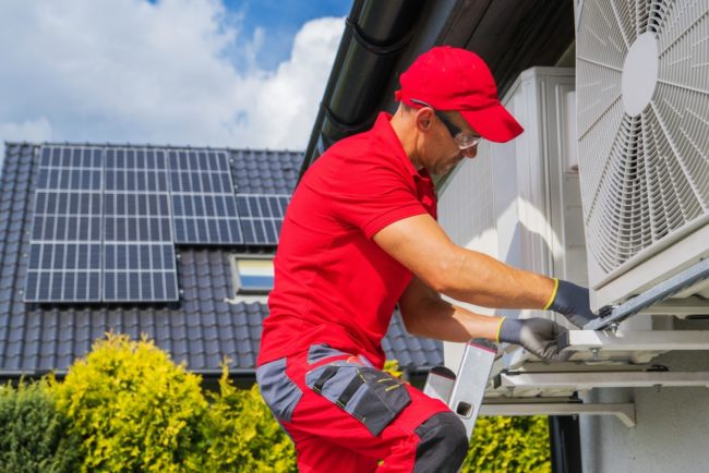 Worker in red servicing a heat pump